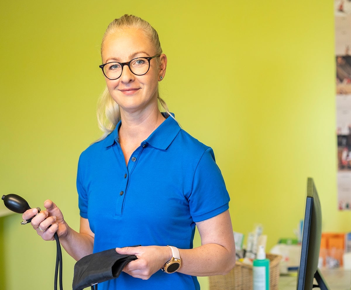 Frau mit blauem Shirt und Blutdruckgerät